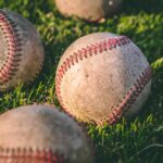 close up photography of four baseballs on green lawn grasses