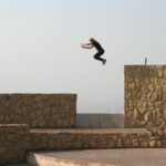 person jumping on beige concrete wall