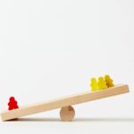 human shape blocks on wooden seesaw