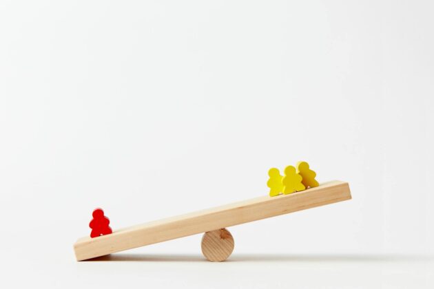 human shape blocks on wooden seesaw