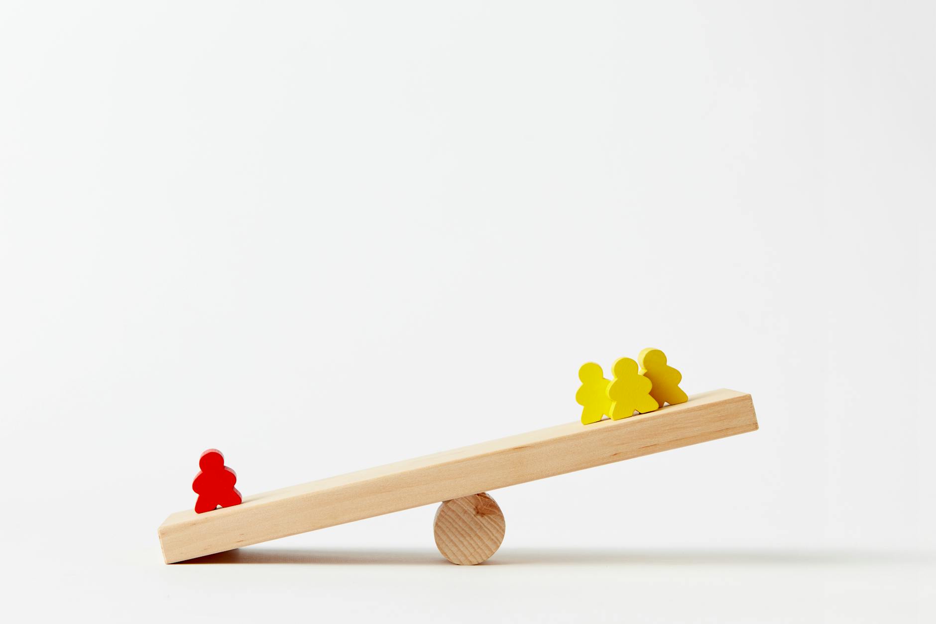 human shape blocks on wooden seesaw